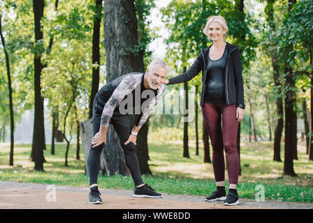 Assez sportif et de la sportive smiling mature à la recherche de concert tout en se tenant dans park Banque D'Images