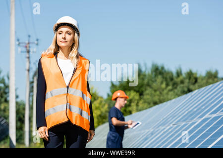 Attractive businesswoman in hardhat gilet de sécurité et à l'écart Banque D'Images
