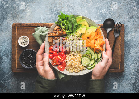 Bol à salade végétarienne Buddha mains mâles sur plateau de service en arrière-plan. Vue d'en haut. Alimentation saine et équilibrée l'alimentation Banque D'Images