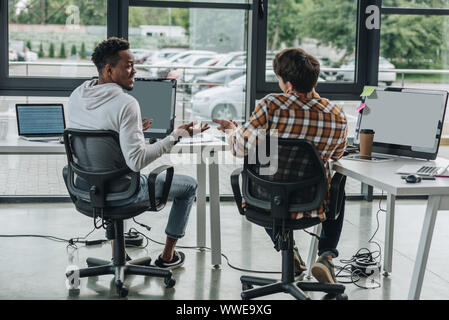 Deux jeunes programmeurs multiculturelle discuter des idées tout en travaillant ensemble Banque D'Images