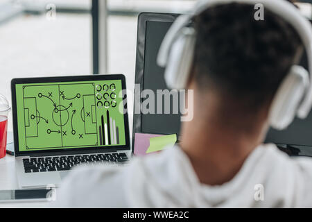 Vue arrière de l'african american programmeur en jouant des écouteurs Football jeu vidéo Banque D'Images