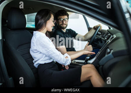 Vendeuse chez le concessionnaire showroom de parler avec le client et l'aider à choisir une nouvelle voiture pour lui-même. Banque D'Images