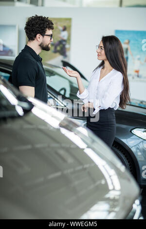 Jeune femme car sales consultant travaillant en salle d'exposition Banque D'Images