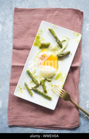 Oeufs pochés cuits sous vide à 64,5 degrés pour la parfaite consistance, sur un plat blanc rectangulaire avec une purée d'asperges et asperges,Télévision Banque D'Images