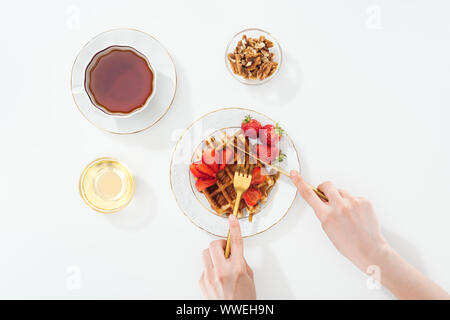 Portrait de femme waffle coupe sur la plaque près de tasse de thé et un bol blanc sur Banque D'Images