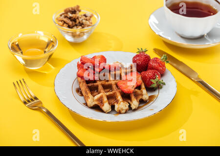 Petit-déjeuner servi avec waffle, fraises, miel, noix et d'un plateau sur jaune Banque D'Images