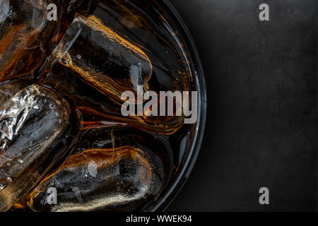 Verre de coke avec des cubes de glace sur fond de pierre sombre Banque D'Images