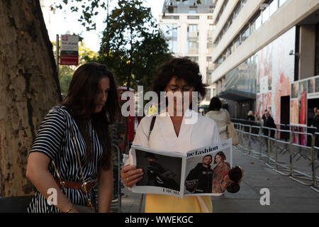 Londres, Royaume-Uni. 15 Septembre, 2019. Deux visiteurs français à la London Fashion Week lire un magazine de mode avant l'exposition au magasin X sur 180 Strand, London. Crédit : Joe Keurig / Alamy News Banque D'Images