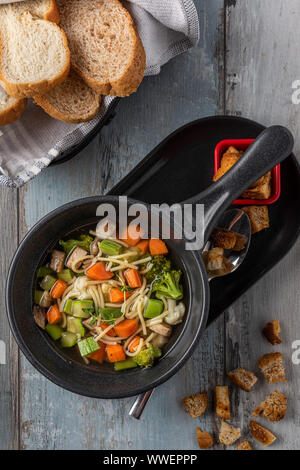 Soupe minestrone chaud servi avec pain crouton sur table en bois Banque D'Images