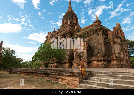 Photo horizontale de happy woman sitting in front of old temple bouddhiste à Bagan, Myanmar Banque D'Images