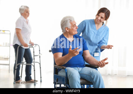 Le fournisseur de jeunes à la mobilité après mature man in nursing home Banque D'Images