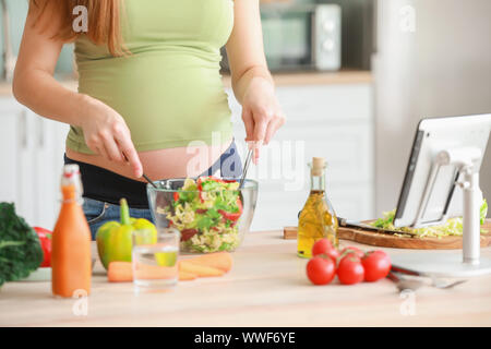 Belle femme enceinte faire salade saine dans la cuisine Banque D'Images