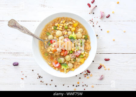 Soupe savoureuse avec les légumineuses dans un bol sur le tableau blanc Banque D'Images