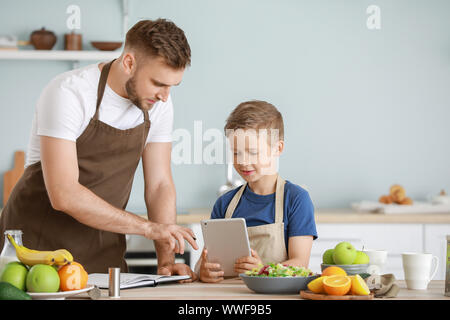 Portrait of happy father and son cooking in kitchen Banque D'Images