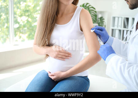 Médecin vaccinant pregnant woman in clinic Banque D'Images