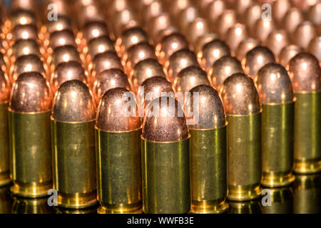 Rangées de munitions d'armes de poing sur fond noir avec reflet Banque D'Images