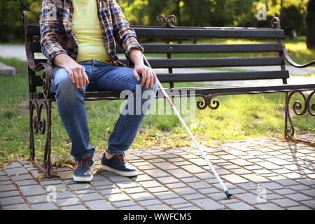 Blind Man sitting on bench in park Banque D'Images