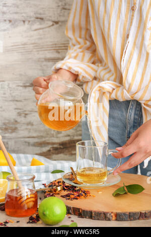 Woman pouring savoureux de boisson chaude dans la théière tasse à table Banque D'Images