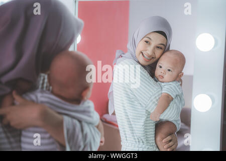 Femme musulmane avec hijab jouer avec son bébé à la recherche dans le miroir Banque D'Images