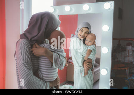 Femme musulmane avec hijab jouer avec son bébé à la recherche dans le miroir Banque D'Images