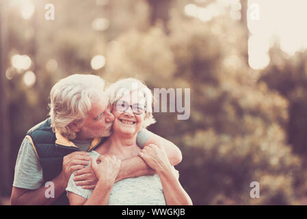 Couple d'heureux et joyeux les gens portrait hauts hug avec amour et sourire avec la forêt verte de flou artistique en arrière-plan - activité de loisirs de plein air pour Banque D'Images