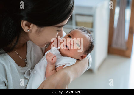 Close up Mère embrassant bébé fille dans la chambre Banque D'Images