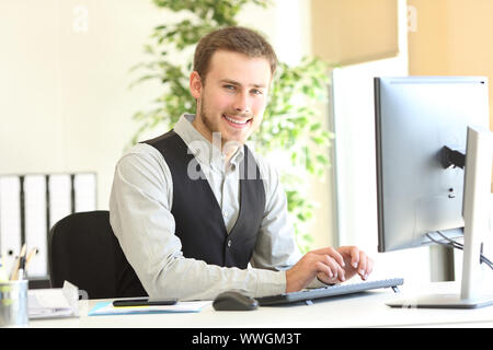 Heureux de poser à la caméra à l'exécutif avec les mains sur le clavier de l'ordinateur de bureau à Banque D'Images