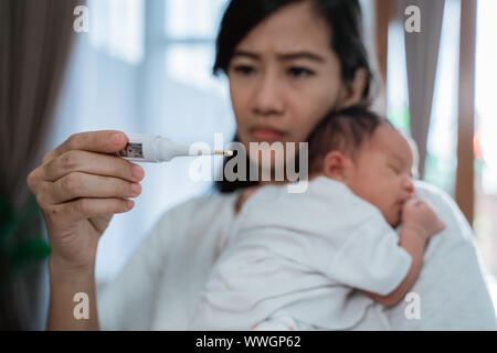 À l'aide de mère asiatique se sentent inquiets thermomètre de la santé de leurs enfants à la chambre Banque D'Images