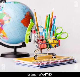 Panier avec des fournitures scolaires avec world globe on white Banque D'Images