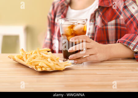 Femme avec verre de cola froid et frites à table Banque D'Images