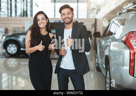 Beautiful brunette woman manager et son bel homme collègue debout dans le centre de l'affaire après affaire réussie montrant des signes comme se sentir heureux Banque D'Images