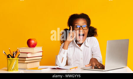 School Girl Doing Homework At Laptop Raising Hand in Studio Banque D'Images