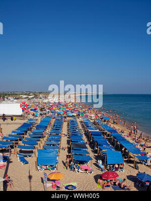 Les personnes de tous âges appréciant la foule la plage de Faro en Algarve du Portugal sur une maison de vacances locales. Banque D'Images