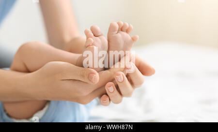 Petits pieds d'un bébé nouveau-né de mère attentive. Banque D'Images