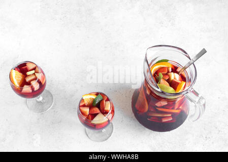 Vin rouge sangria ou punch aux fruits et de la glace dans les verres et pichet. Des fruits rafraîchissante sangria sur fond blanc, copie de l'espace. Banque D'Images