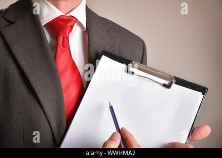 L'homme en costume avec cravate rouge montrant un dossier avec des feuilles vierges avec brown isolated background. Composition horizontale. Vue de face. Banque D'Images