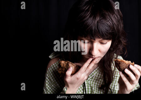 Portrait d'un pauvre mendiant femme mangeant du pain dans ses mains Banque D'Images