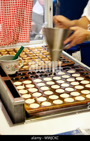 De délicieux aliments hollandais authentiques des Pays-Bas appelé poffertjes, qui sont des mini-crêpes, en préparation sur une plaque chaude typique tandis que cook est po Banque D'Images