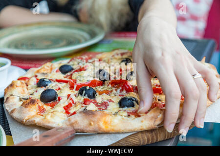 Main femme prise d'une tranche de pizza Banque D'Images