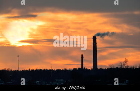 Pipe contre un ciel de coucher du soleil. La fumée va de tuyaux. Fond de Ciel Coucher de soleil rouge Banque D'Images