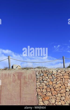 Corde traditionnel clôturer plus de mur de pierre grunge cement blue sky Banque D'Images