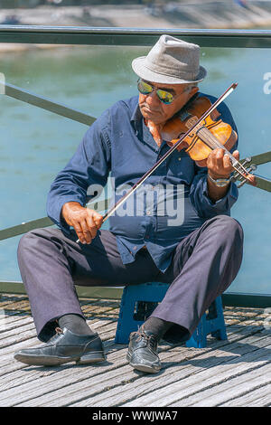 Paris, France - le 4 juillet 2017 : Vieil homme sur un tabouret à jouer du violon pour obtenir des conseils sur le Pont des Arts passerelle au-dessus de la Seine à Paris. Banque D'Images