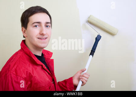 Homme peindre un mur. Peintre dans l'ensemble rouge mur peinture en couleur vert Banque D'Images