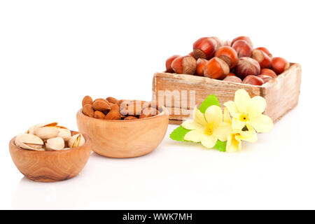 Pistaches, Amandes, noisettes, avec des fleurs dans le bol en bois. Banque D'Images