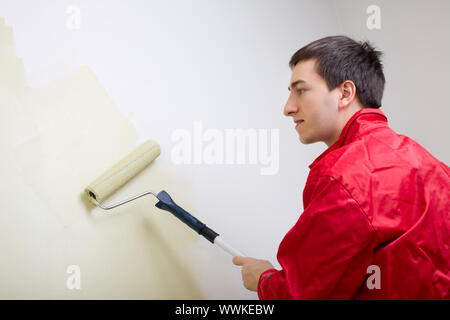 Homme peindre un mur. Peintre dans l'ensemble rouge mur peinture en couleur vert Banque D'Images