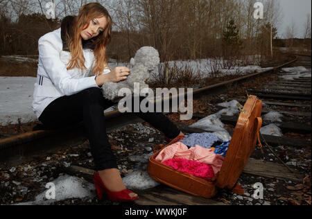 Jeune fille blonde assise sur rail Banque D'Images