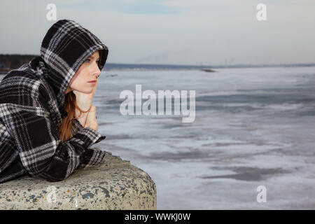 Fille blonde près de la rivière couverte de glace hiver Banque D'Images