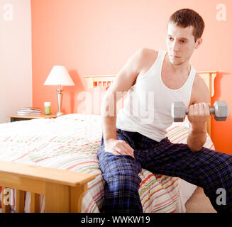 Portrait de l'homme assis sur le lit avec une expression vide et à l'aide d'un bras du poids. Format carré. Banque D'Images