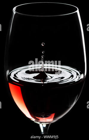 Les gouttes de vin rouge dans un verre de vin rouge Banque D'Images