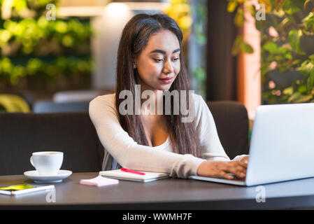 Jolie fille intelligente qui étudient ou travaillent dans la seule cafétéria Banque D'Images